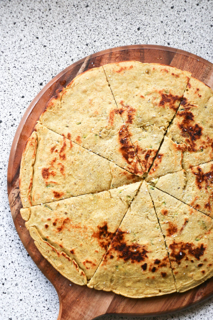 Zucchini breakfast flatbread on a wooden chopping board.